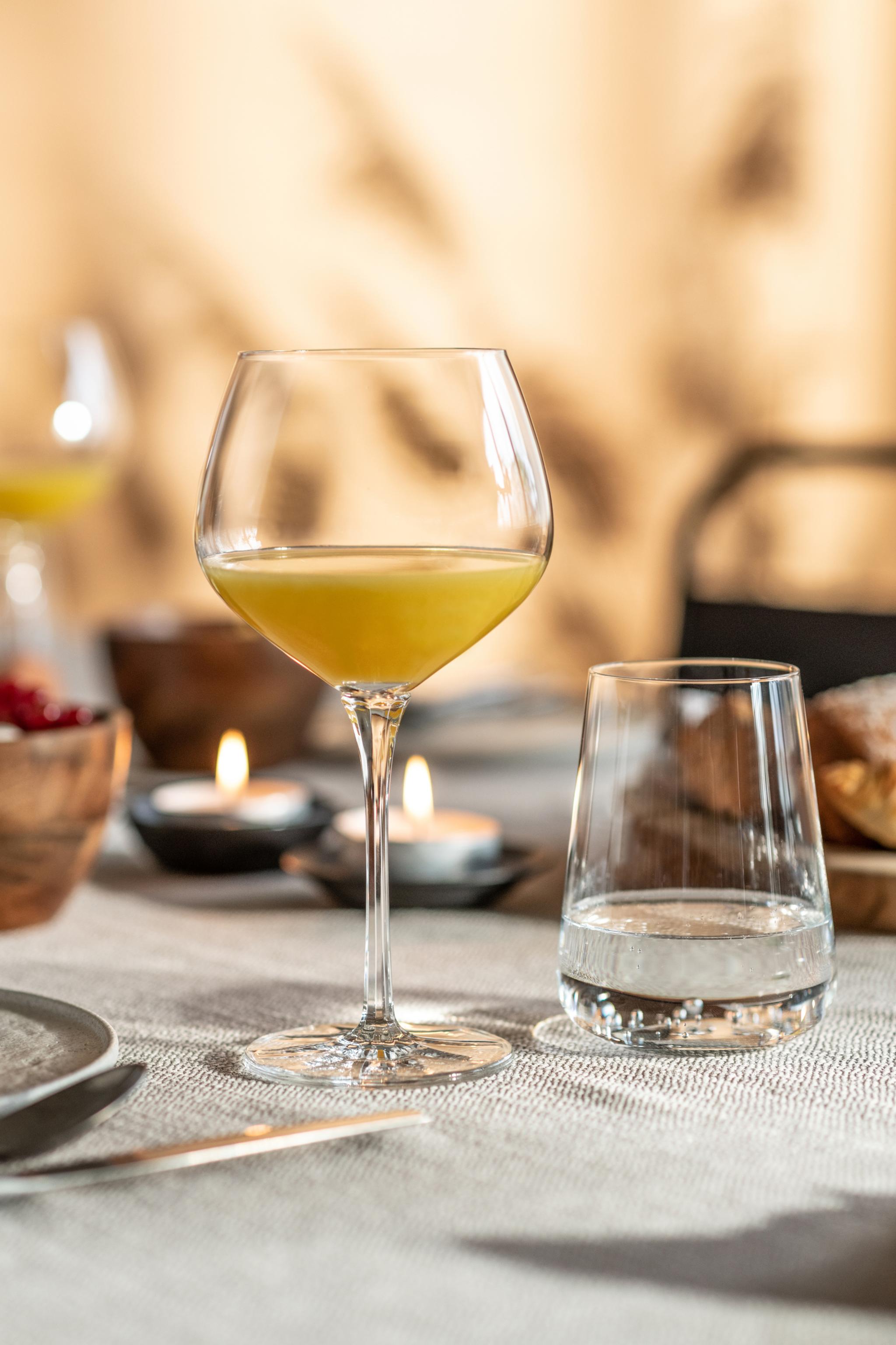 Dukat bord för brunch med ett glas med apelsinjuice i sommarljus