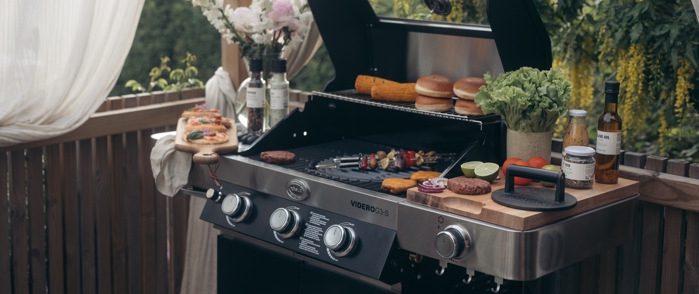 Gasolgrill fullt utrustad med hamburgare och annat grillat