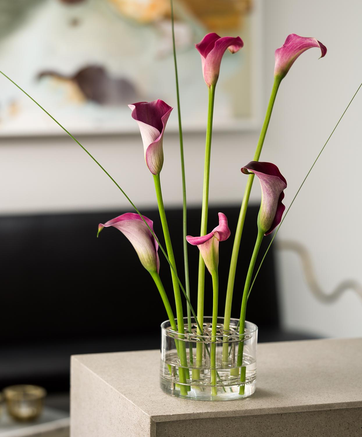 En vas fylld med rosa blommor står på ett bord.