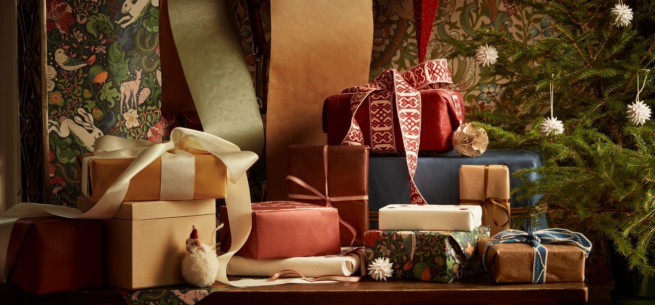 Pino joululahjoja on asetettu pöydälle joulukuusen eteen.