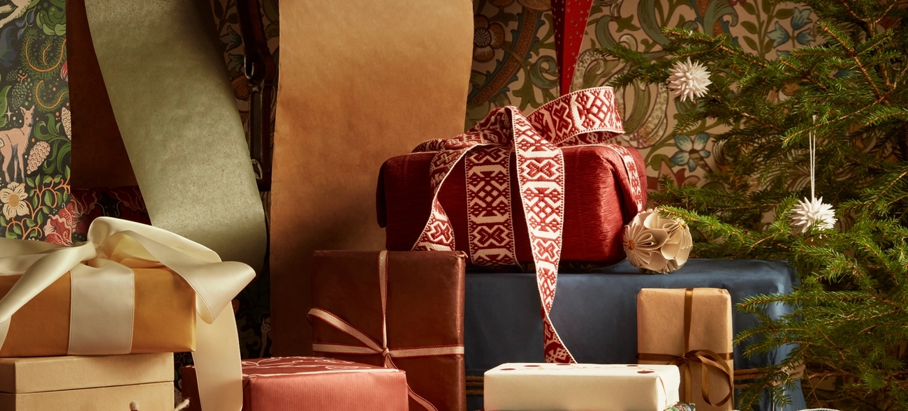 Pino joululahjoja on asetettu pöydälle joulukuusen eteen.