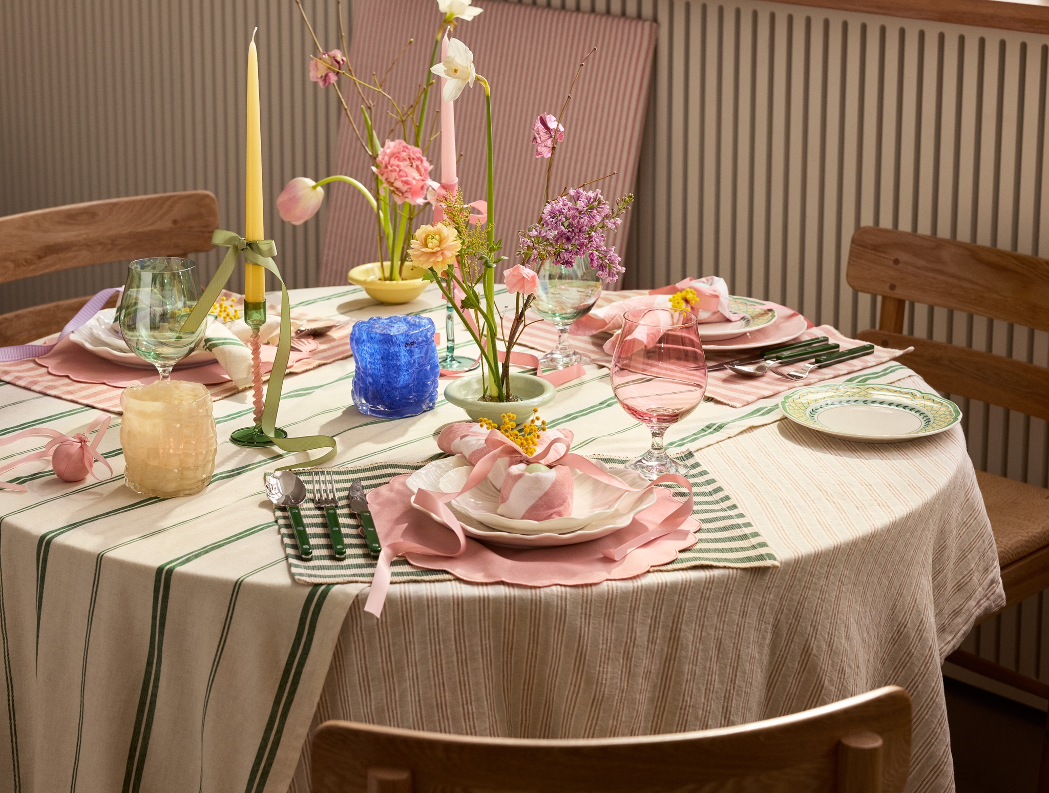 Dukning till påsk på grönrandig duk med vita tallrikar och rosa servetter