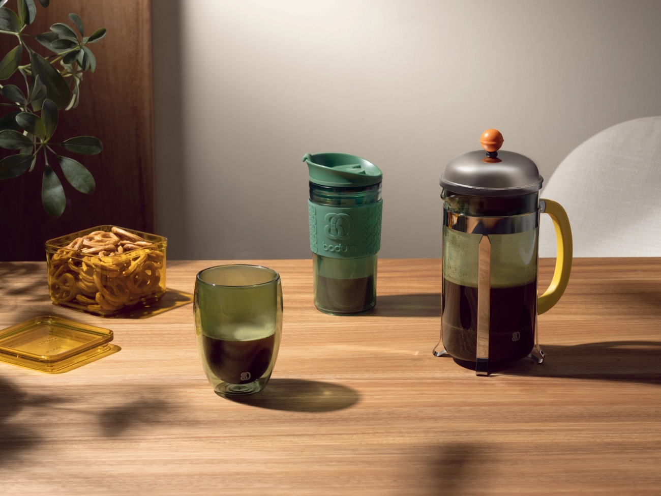 Et trebord med en kopp kaffe, termokopp og en presskanne fra Bodum