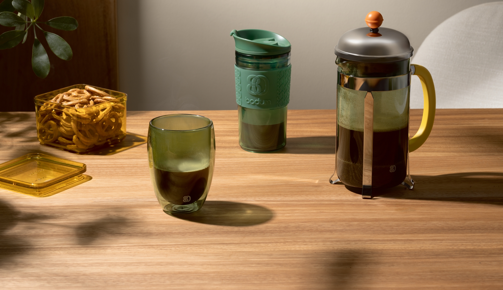 Et trebord med en kopp kaffe, termokopp og en presskanne fra Bodum