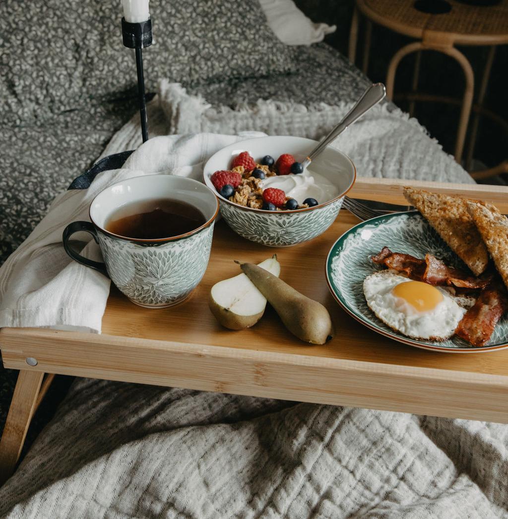 En frukostbricka på sängen med en skål flingor och en kopp te