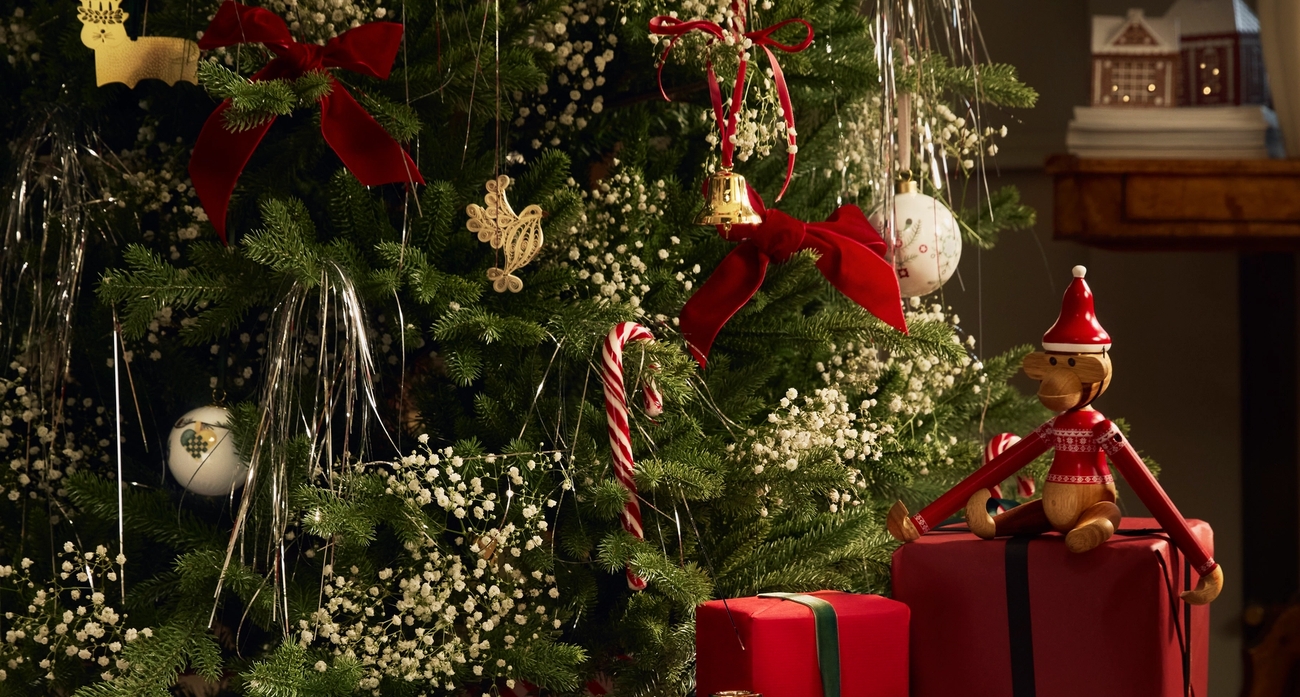 Julegaver med rødt gavepapir ved siden av et pyntet juletre