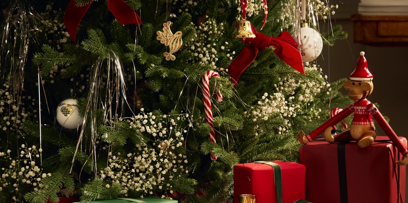 Julegaver med rødt gavepapir ved siden av et pyntet juletre