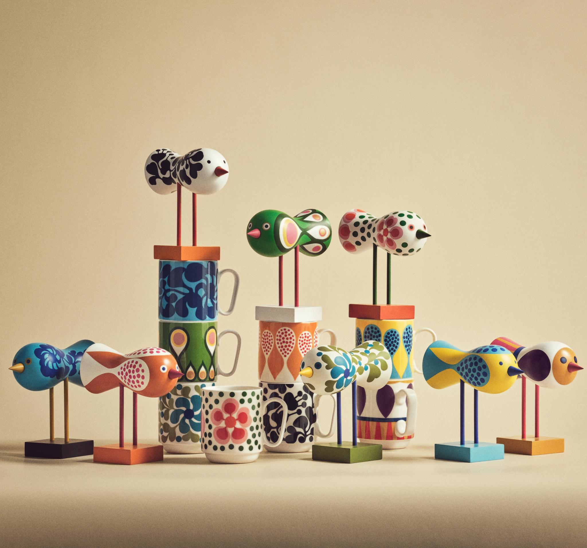 a group of colorful birds sitting on top of stacked mugs .