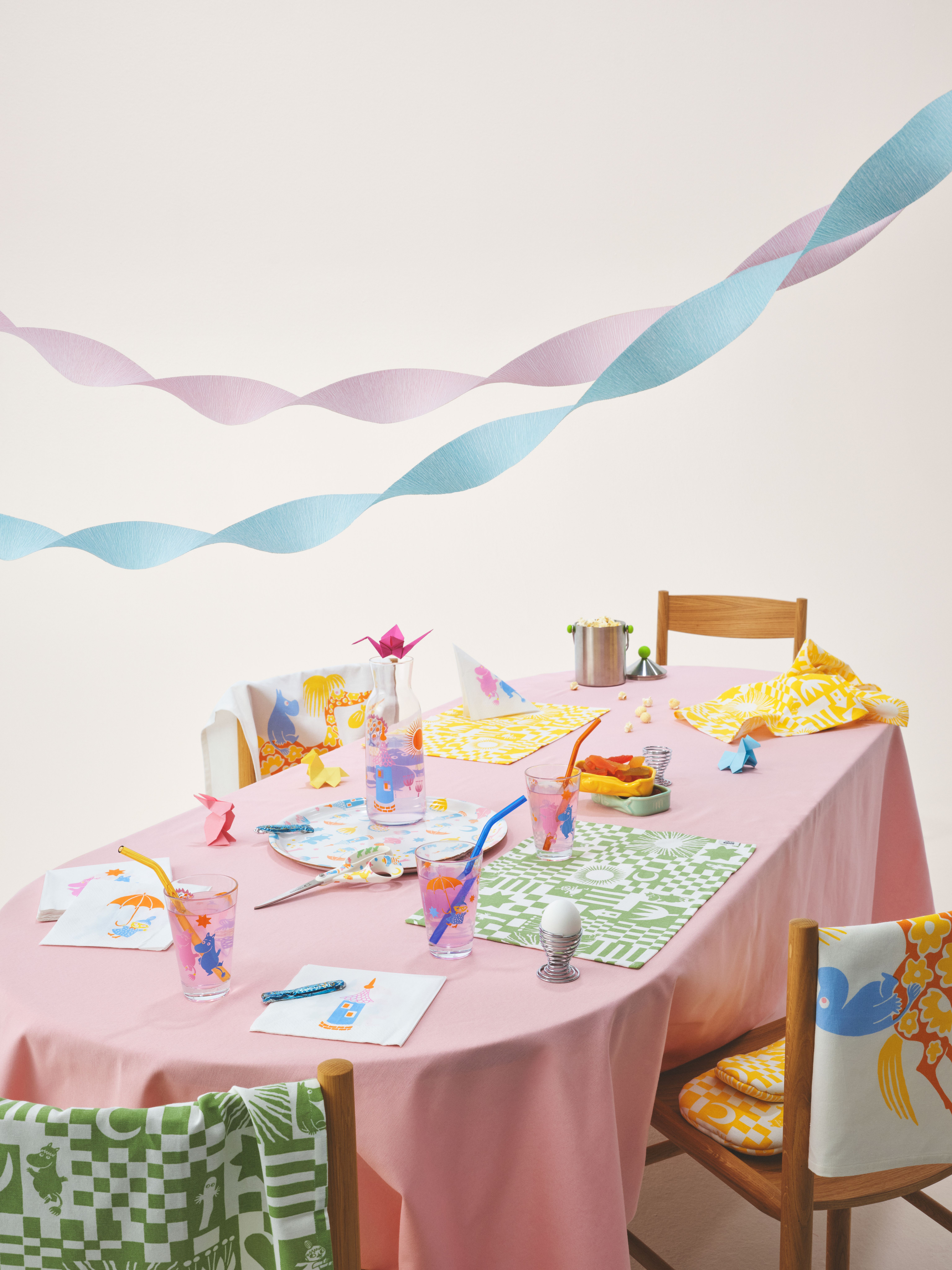 Mummi Festkolleksjon borddekking med glass, karaffel, brett og servietter i pastellfarger på rosa duk