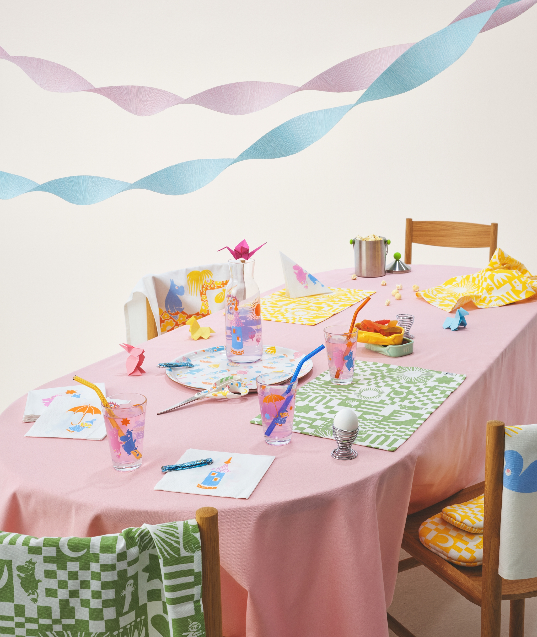 Muumi juhlat kokoelma katetulla pöydällä täynnä pastellivärejä, laseja, servettejä, tarjotin ja pöytätabletit