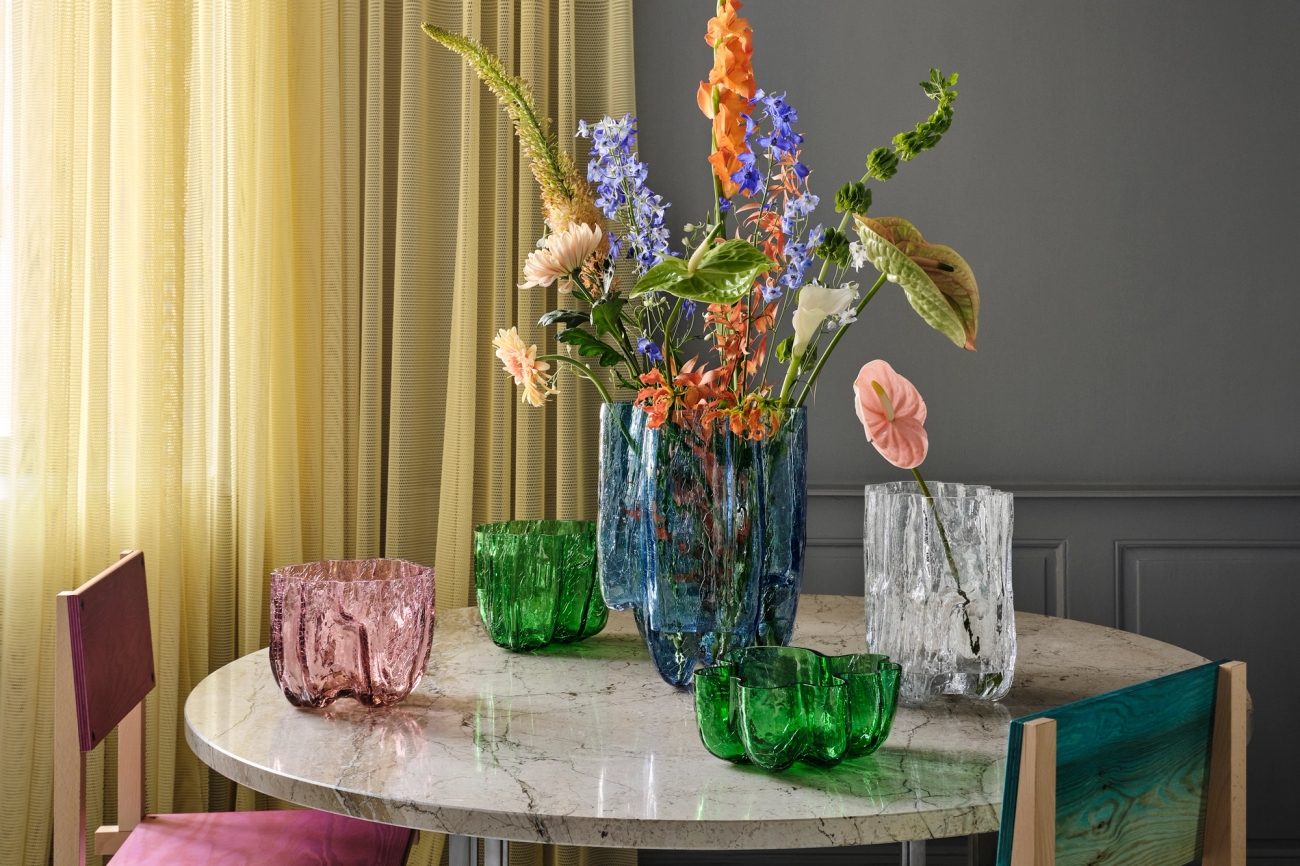 Färgglada glasvaser i grönt, blått och rosa med vackra blommor i.
