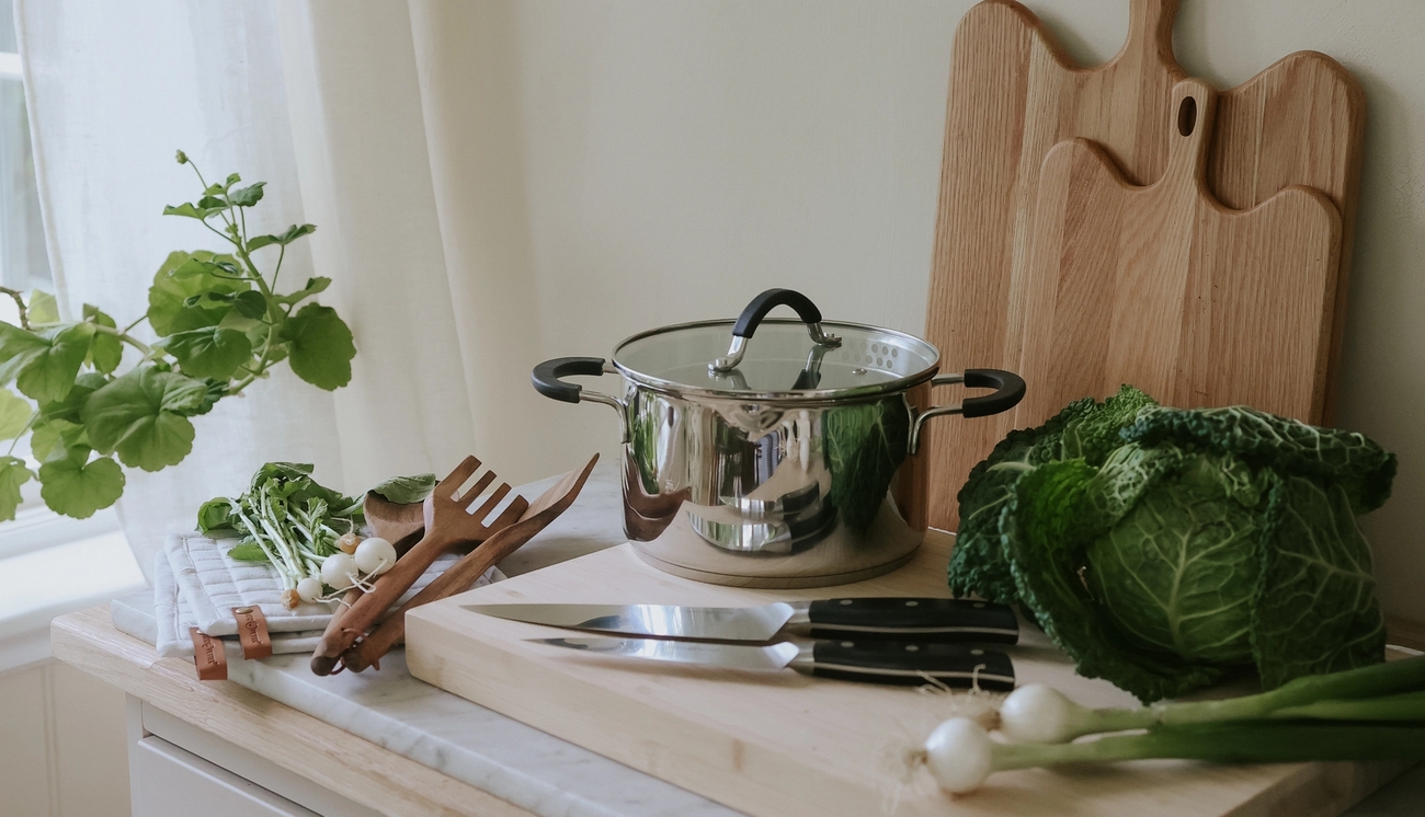 Köksredskap, knivar, skärbräda och kastrull i ett somrigt kök