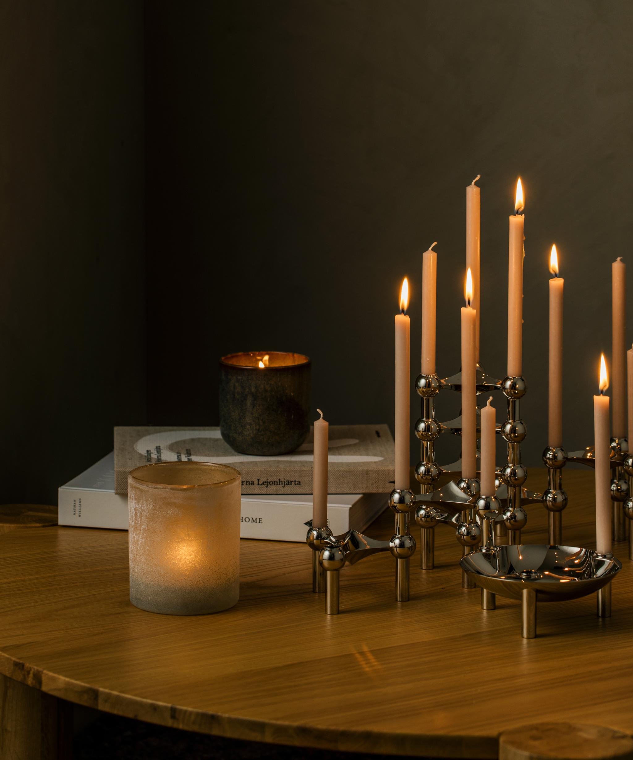 En ljusstake med många tända ljus står på ett träbord
