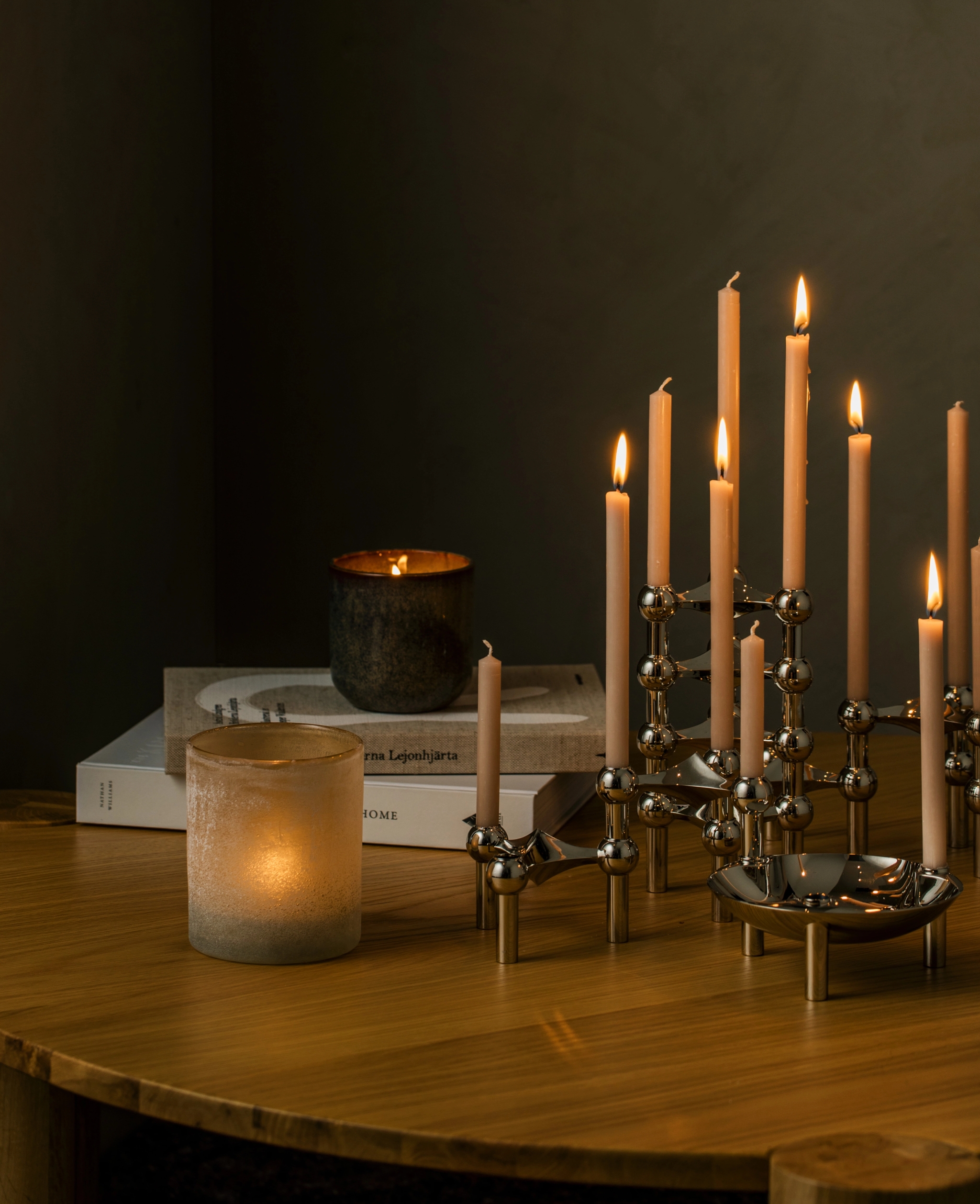 En ljusstake med många tända ljus står på ett träbord