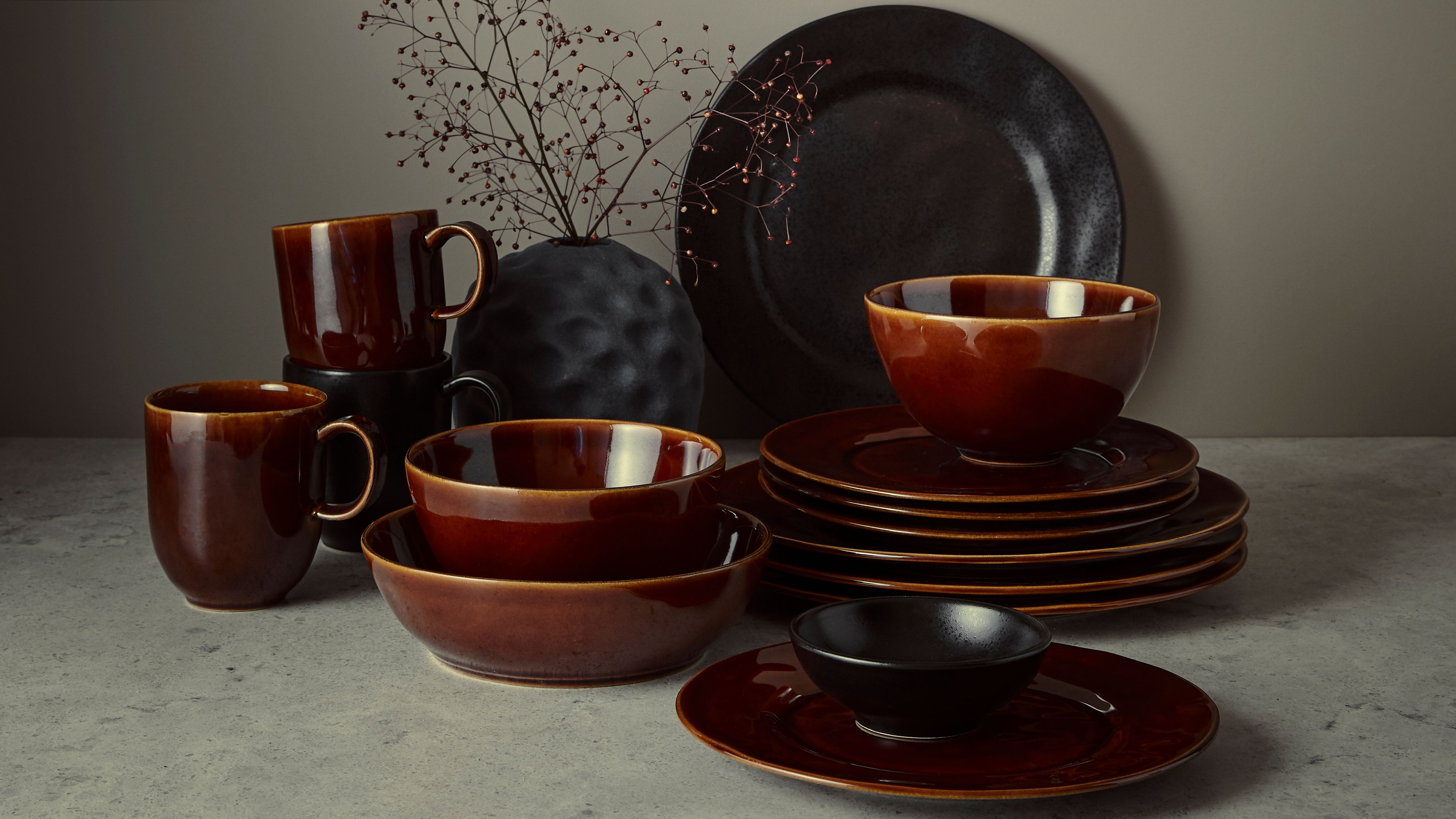 ruskeat lasitetut lautaset kulhot ja kupit harmaalla alustalla