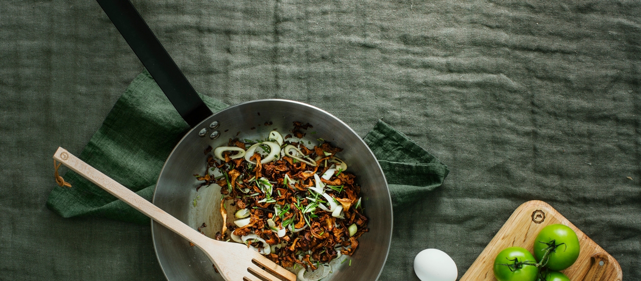 Kolstålspanna med en klick smör och rosmarin i med kantareller