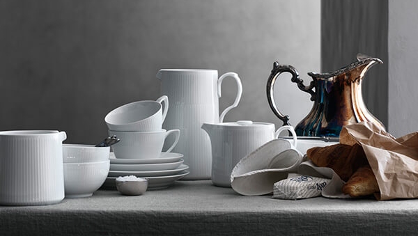 et bord dekket med en rekke hvite tallerkener og en mugge.