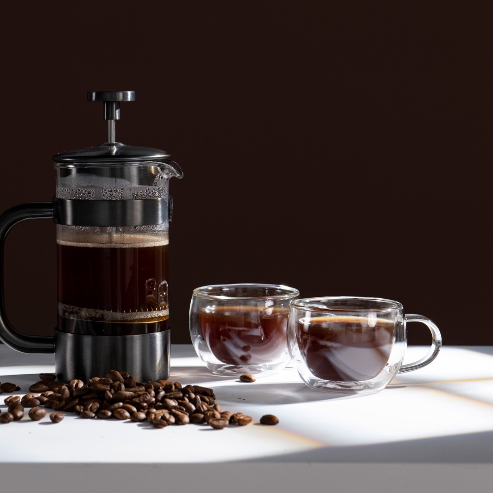 Glasmuggar med kaffe i och en pressobryggare
