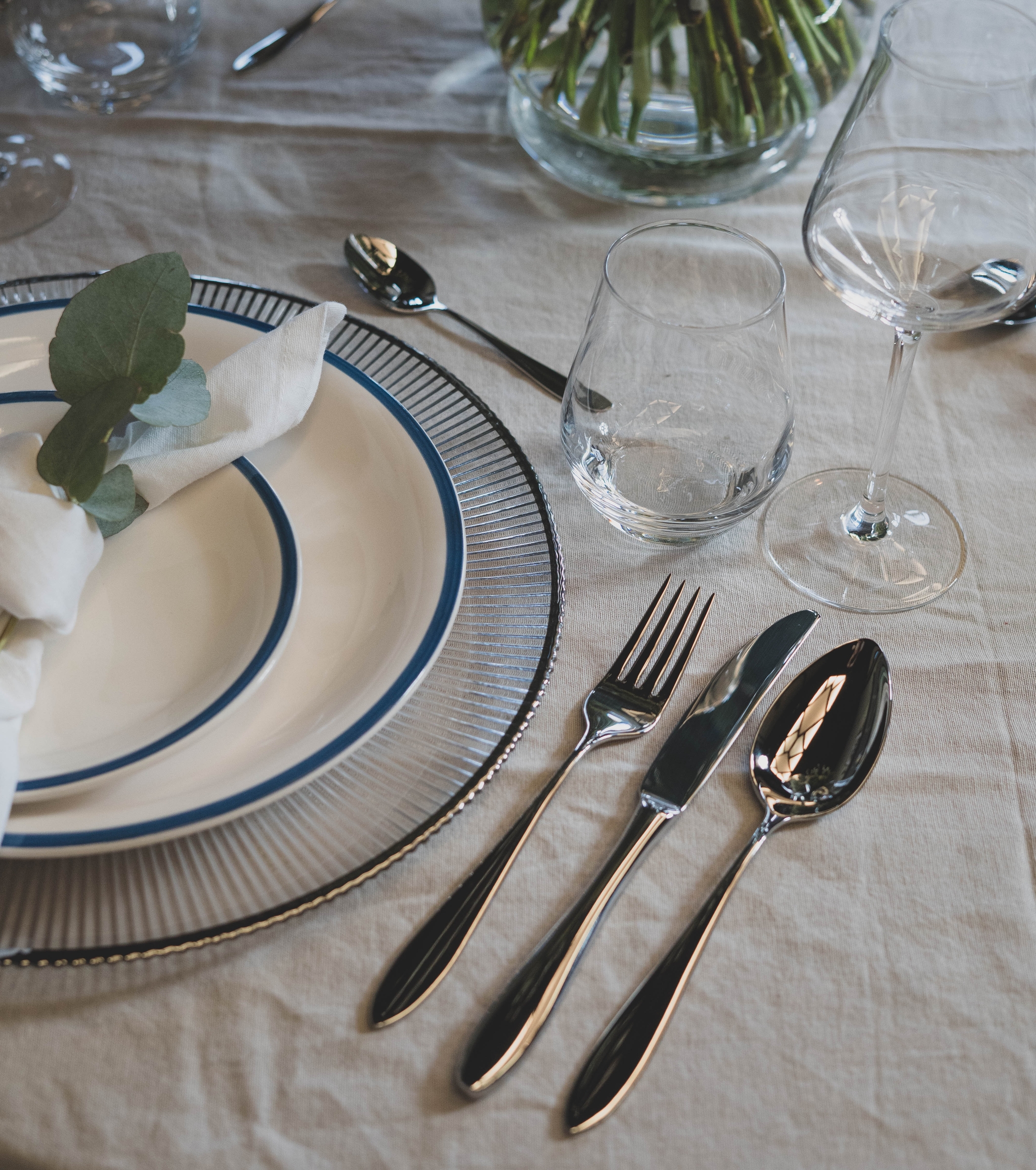 pöytä lautasilla ja aterimilla sekä kukkamaljakko