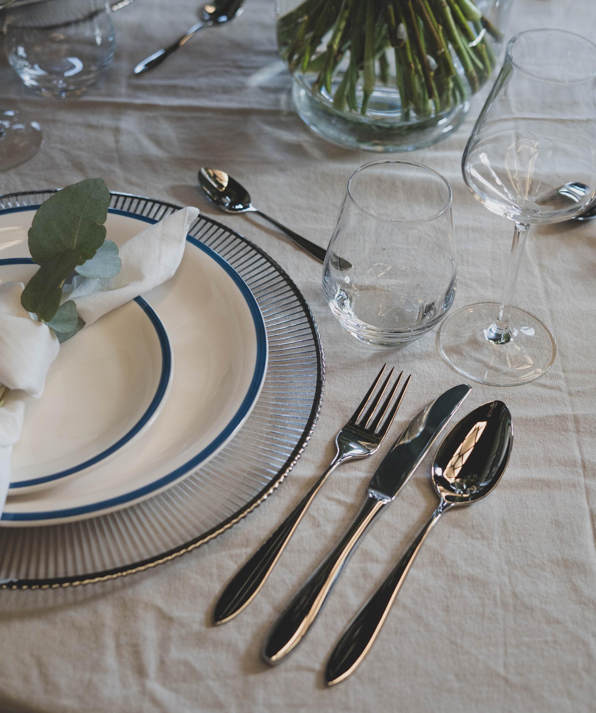 pöytä lautasilla ja aterimilla sekä kukkamaljakko