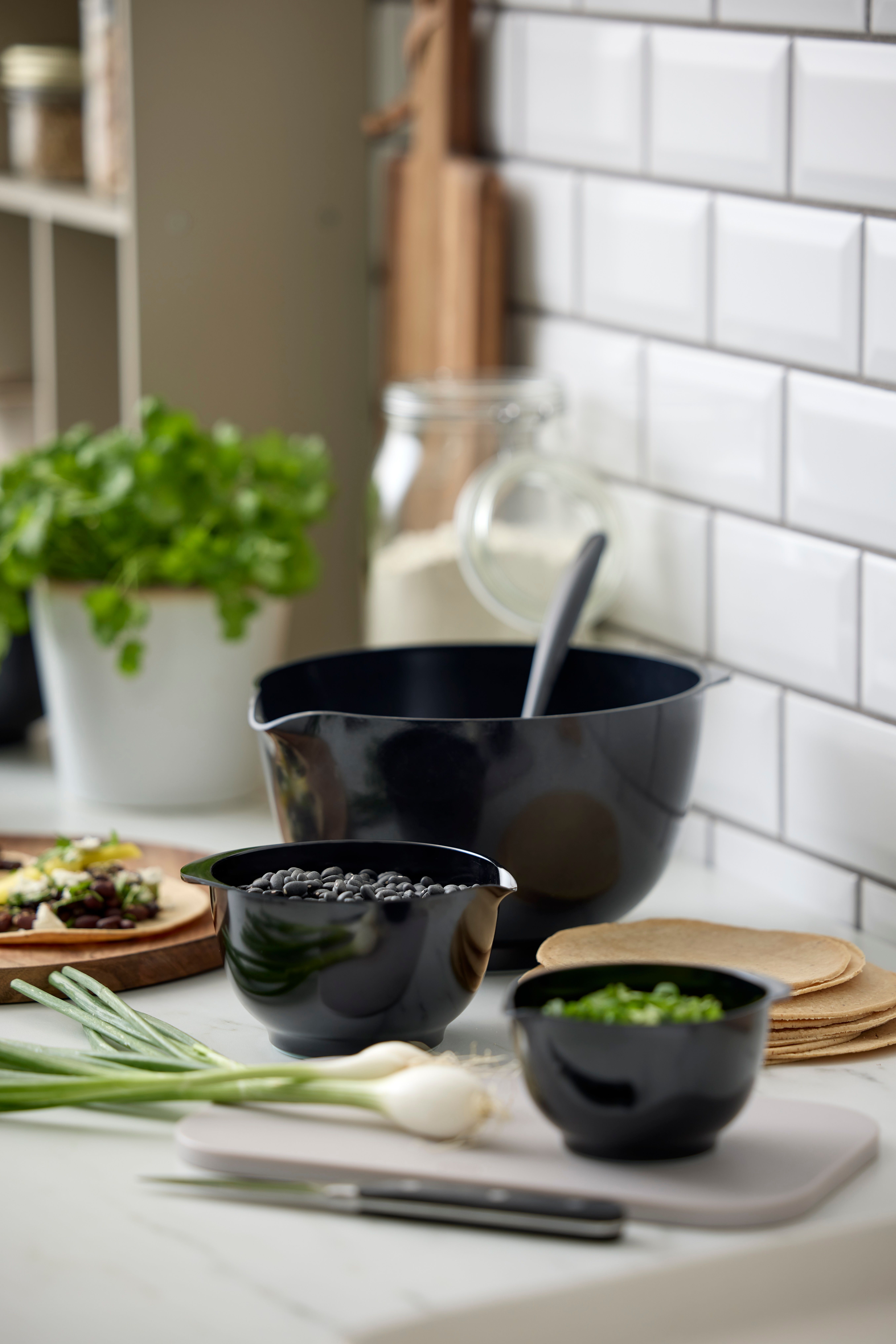 Tilberedning av taco på kjøkkenet med svarte bønner, vårløk, tortillas og friske urter.