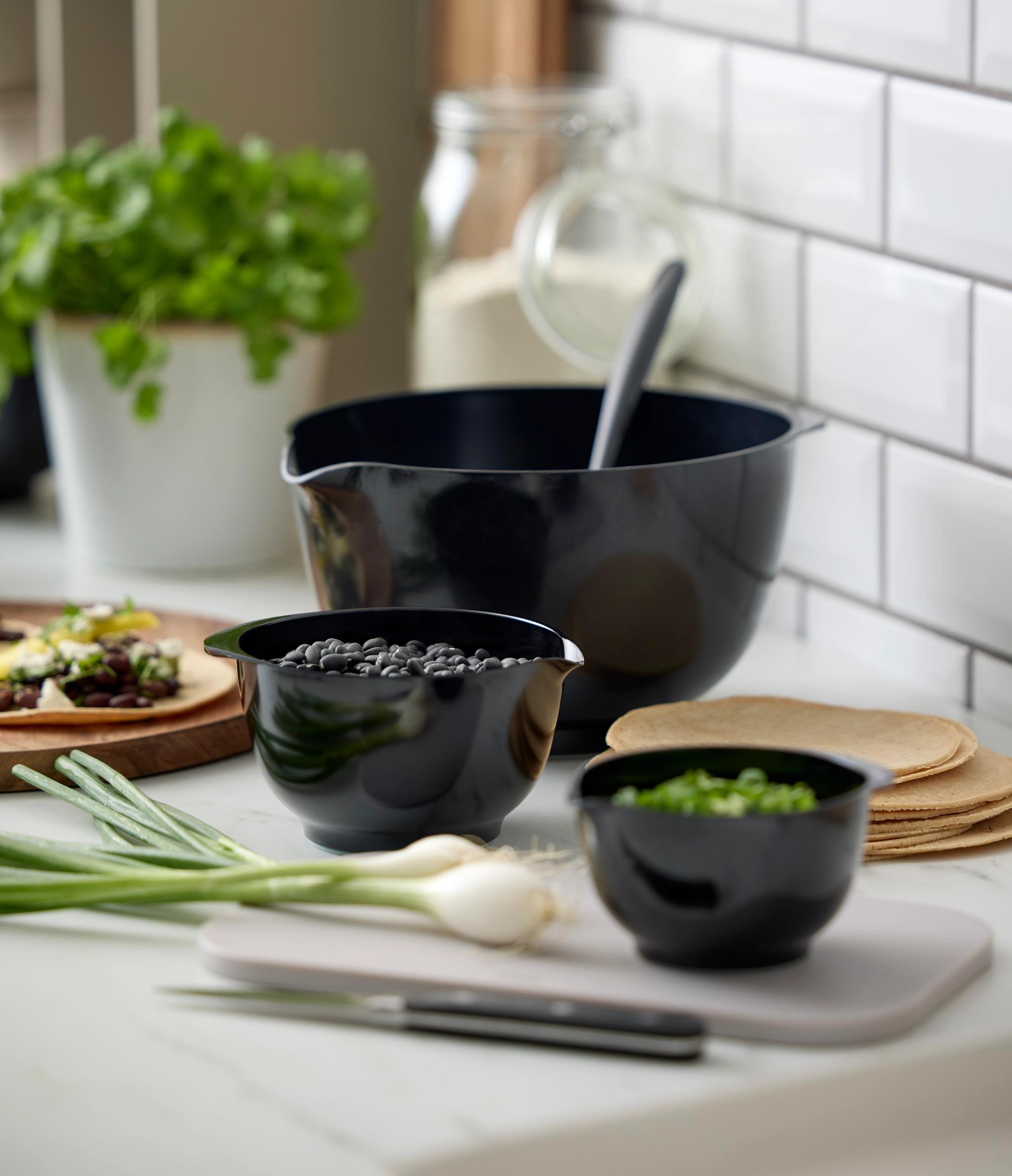 Tilberedning av taco på kjøkkenet med svarte bønner, vårløk, tortillas og friske urter.