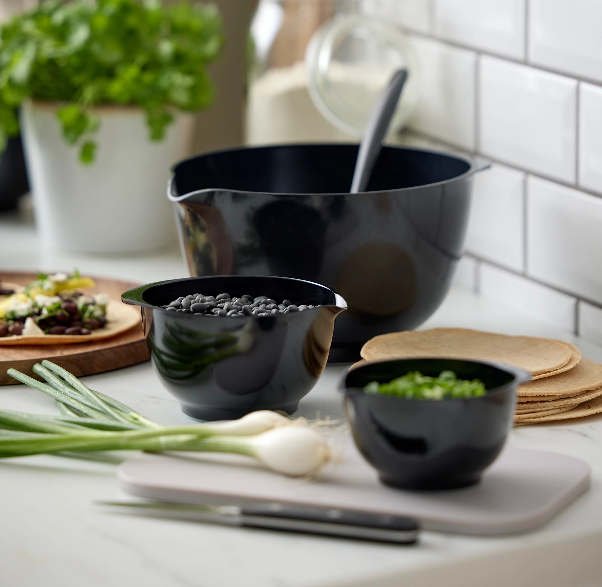 Tilberedning av taco på kjøkkenet med svarte bønner, vårløk, tortillas og friske urter.