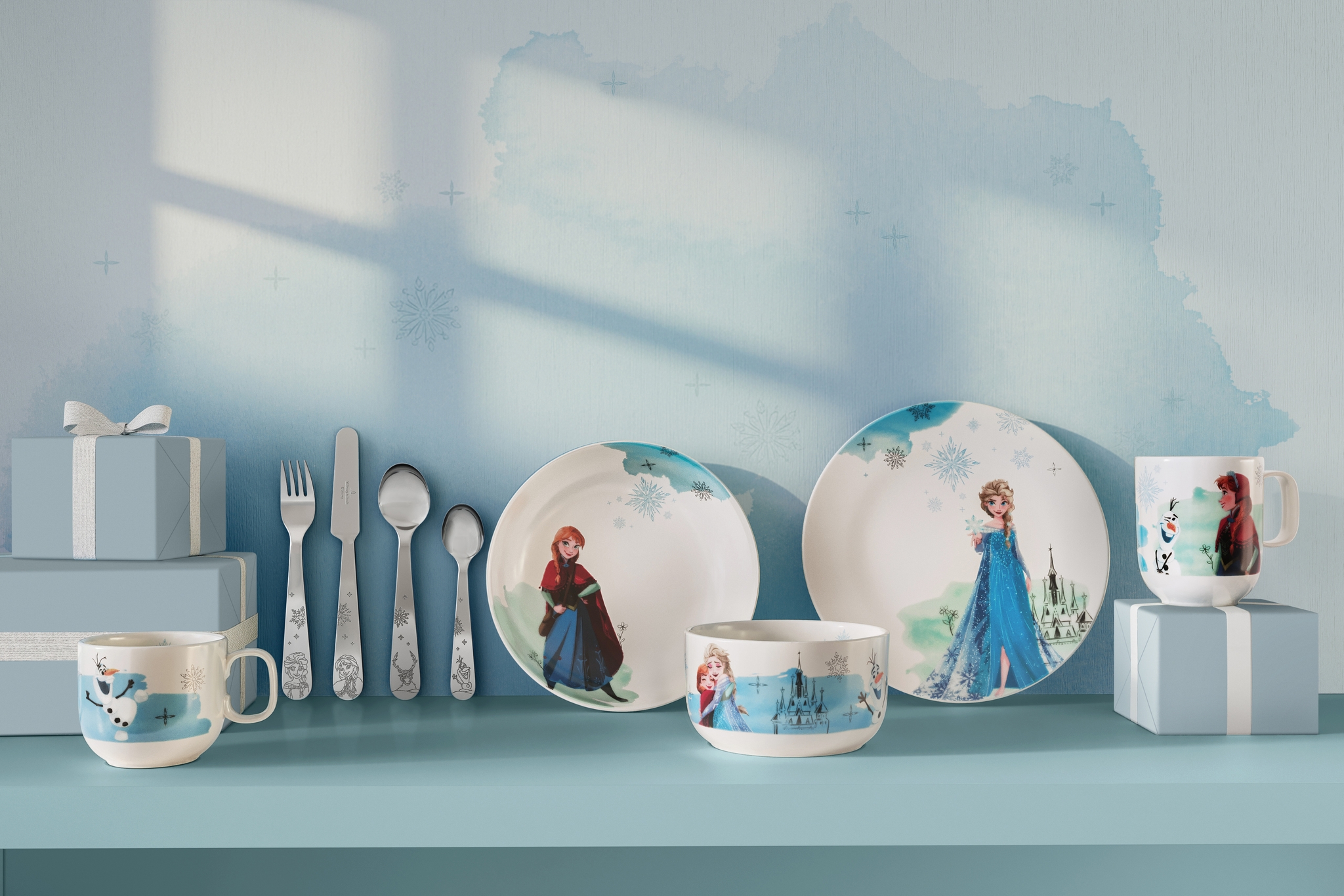 Disney Frost-servise med tallerkener, kopper og bestikk med motiv av Elsa, Anna og Olaf på en lyseblå hylle.