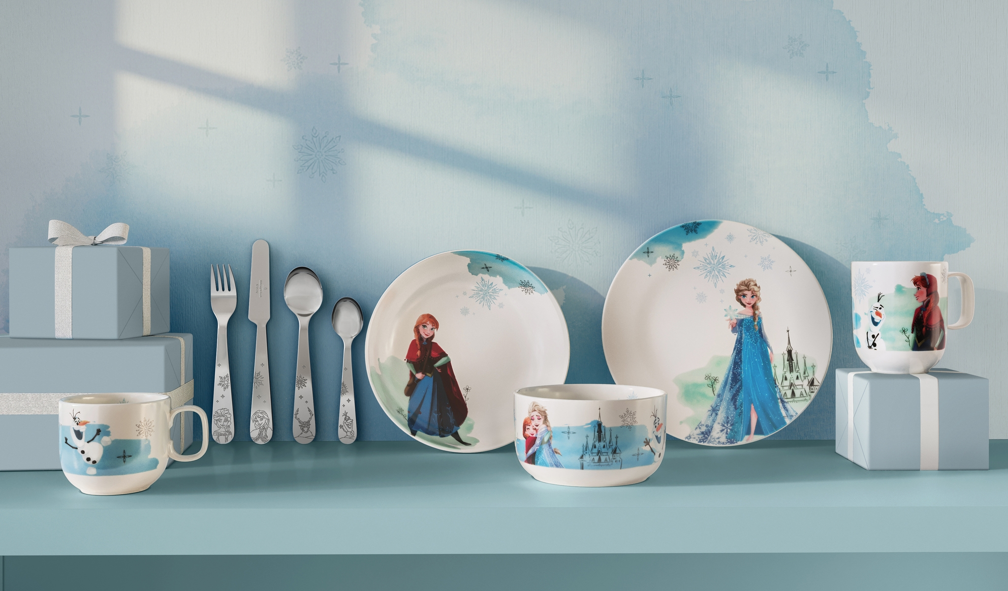 Vaaleansinisellä hyllyllä on Frozen-teemainen lasten astiasto ja lahjapakkauksia, joissa on Annan, Elsan ja Olafin kuvituksia.
