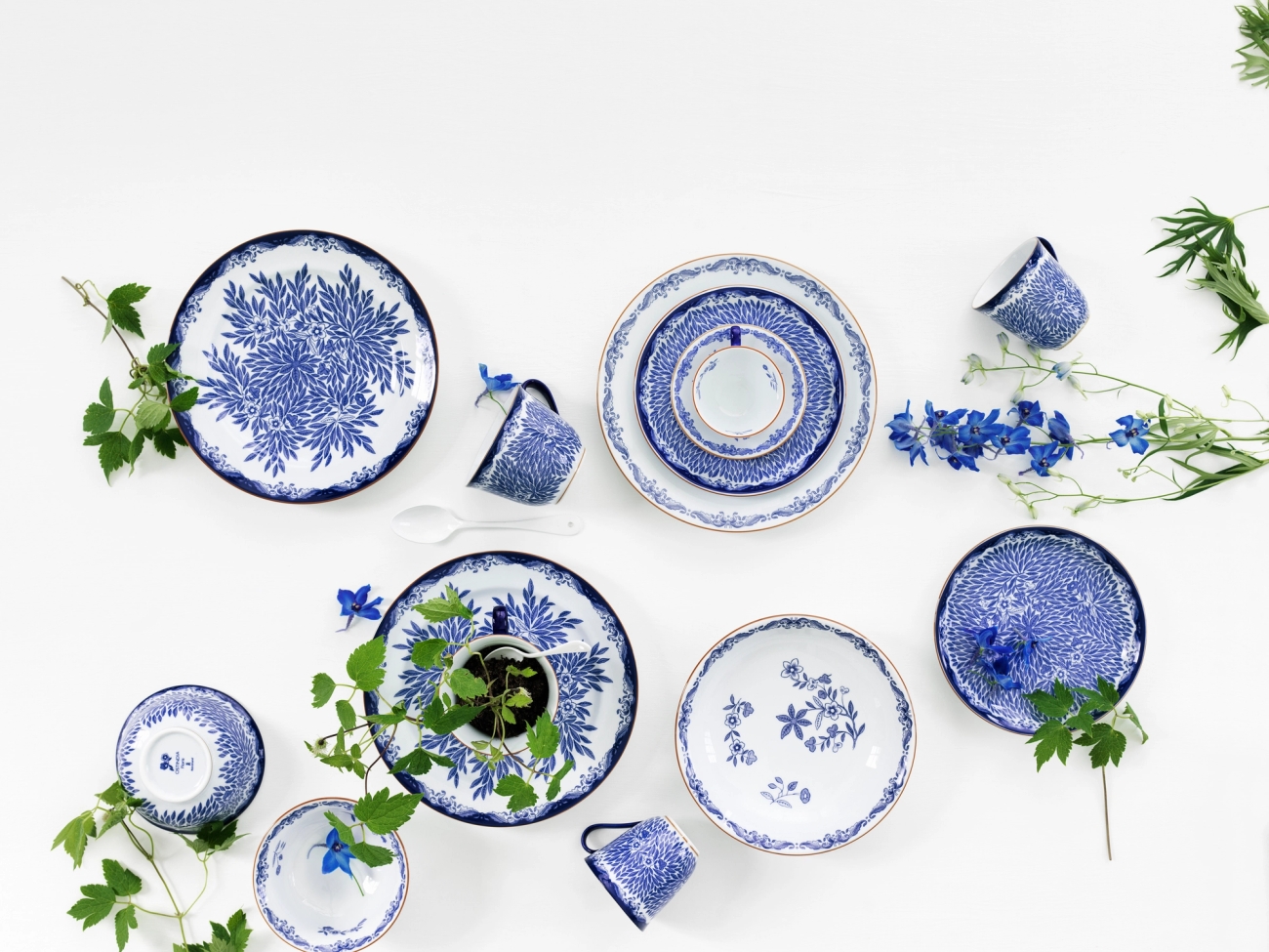 a table topped with blue and white plates , cups , and flowers .