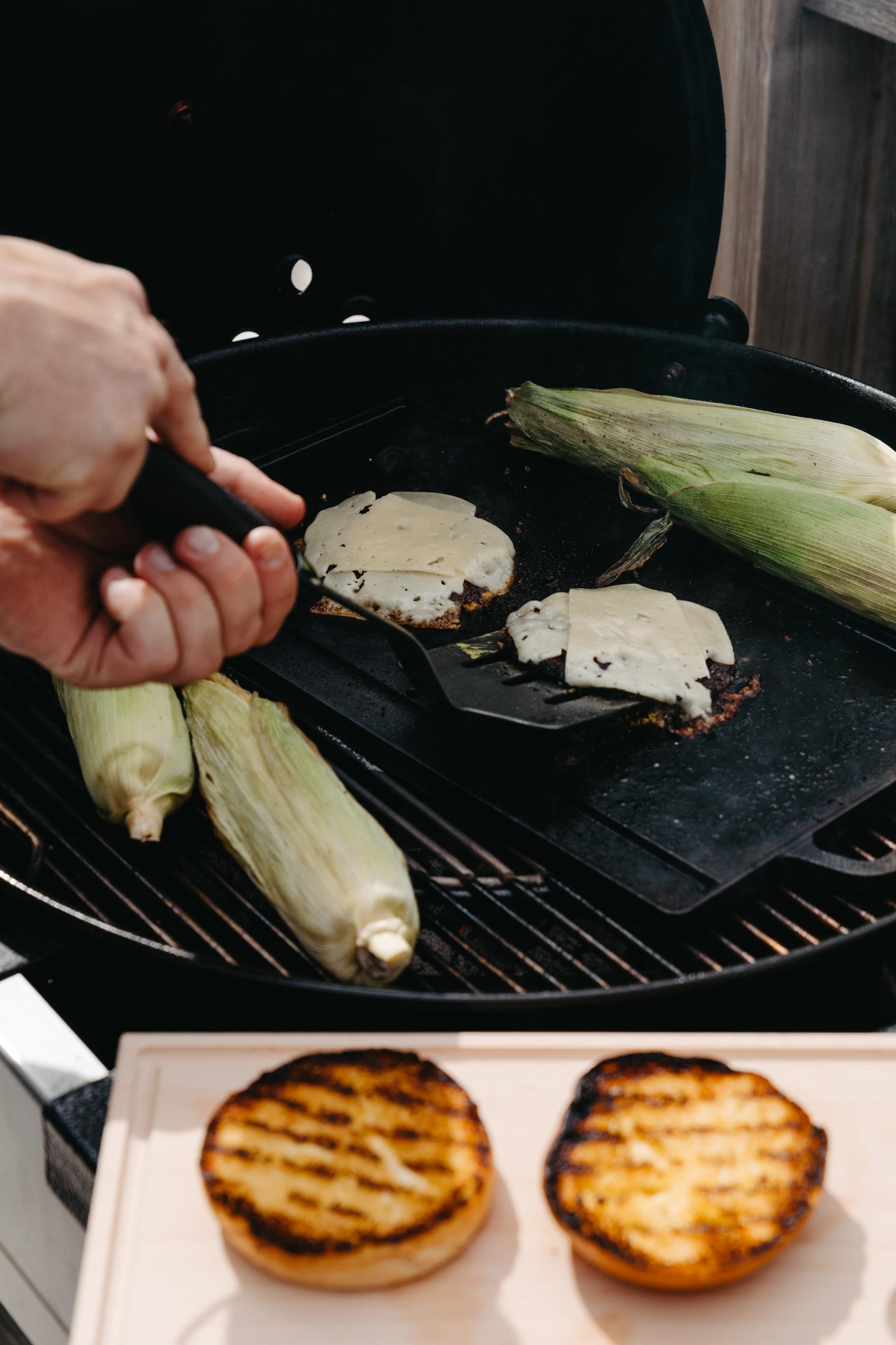 Hamburgare och majskolvar som grillas på grillen