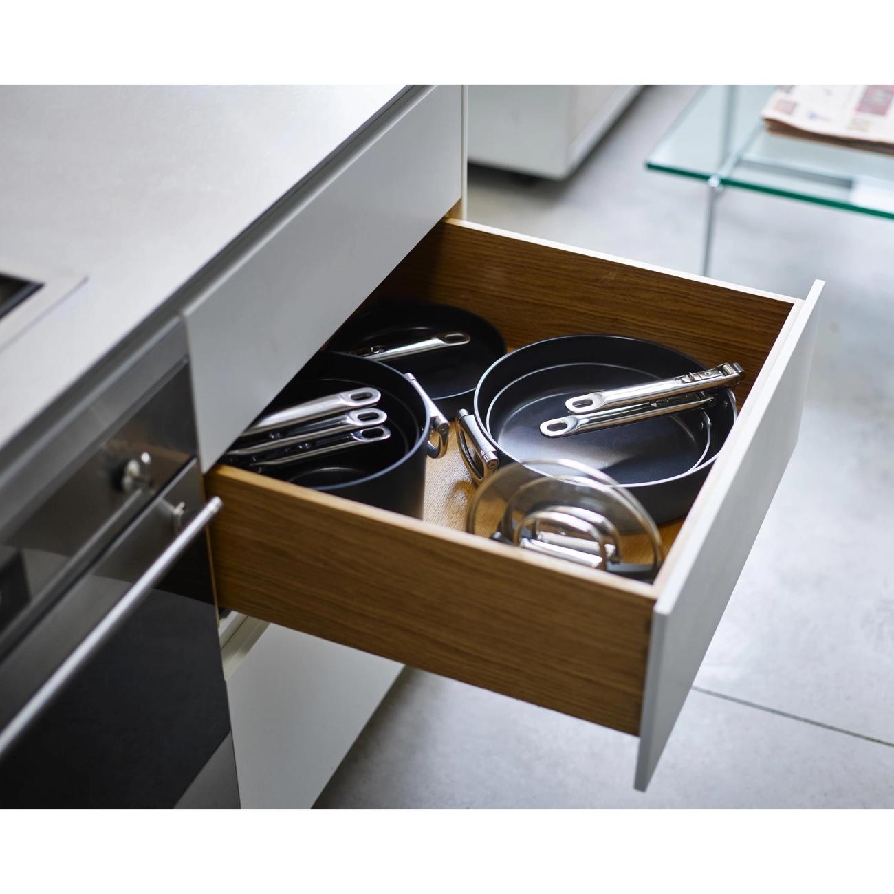 Open kitchen drawer with nested pots, pans, and lids.