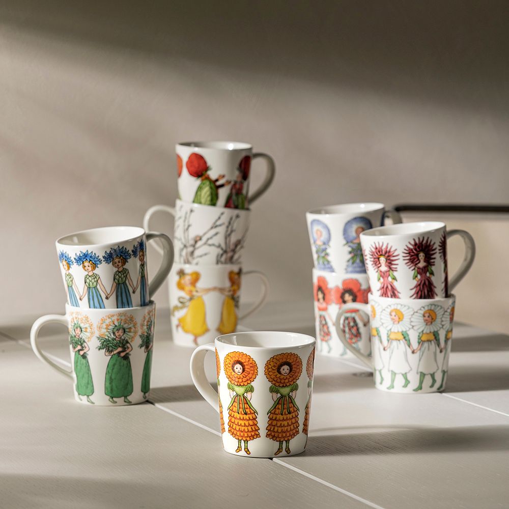 Valkoisia mukeja värikkäillä ja oikukkailla kuvioilla, osa pinottuina, vaalealla alustalla.