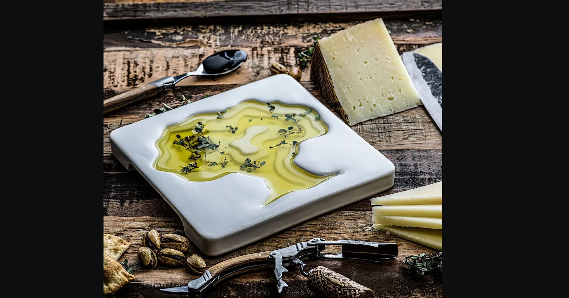a white plate with olive oil and cheese on a wooden table .