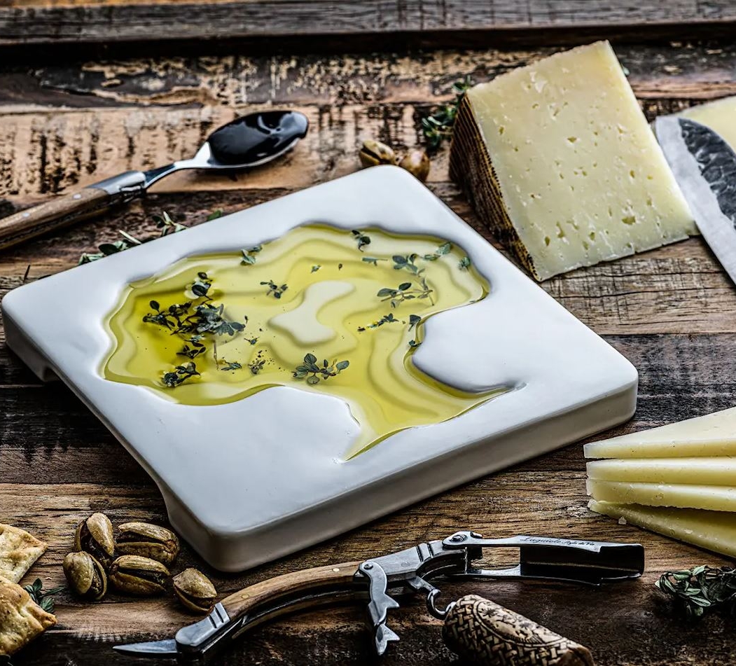 a white plate with olive oil and cheese on a wooden table .