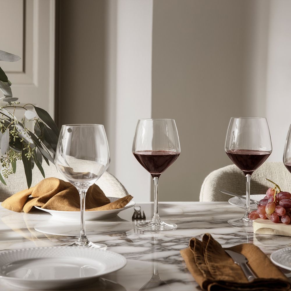 Elegant dukat marmorbord med vinglas, linneservetter och druvor i en ljus matsal.