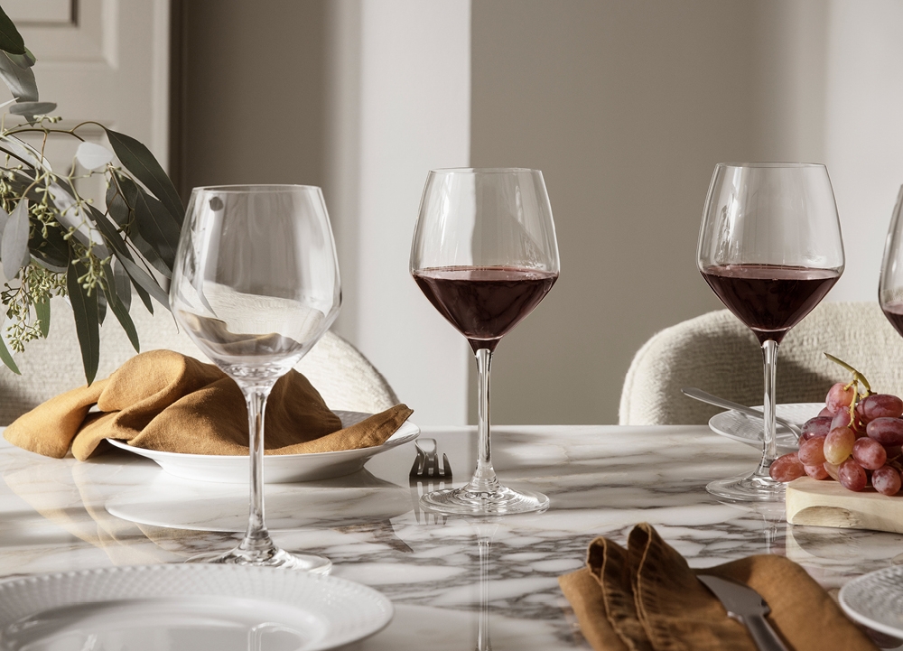Elegant dukat marmorbord med vinglas, linneservetter och druvor i en ljus matsal.
