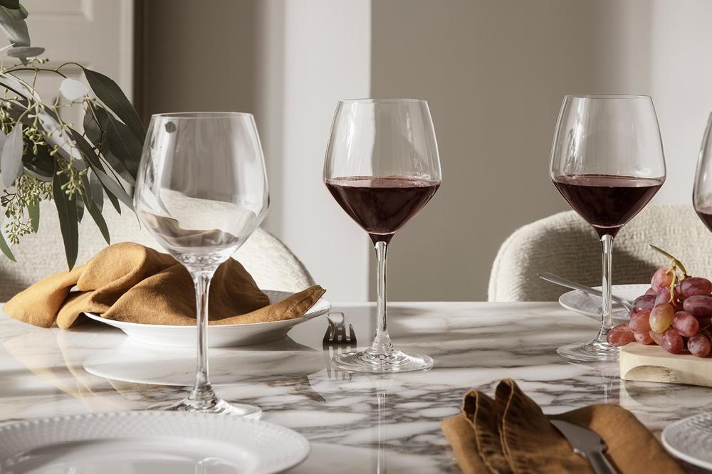 Elegant dukat marmorbord med vinglas, linneservetter och druvor i en ljus matsal.