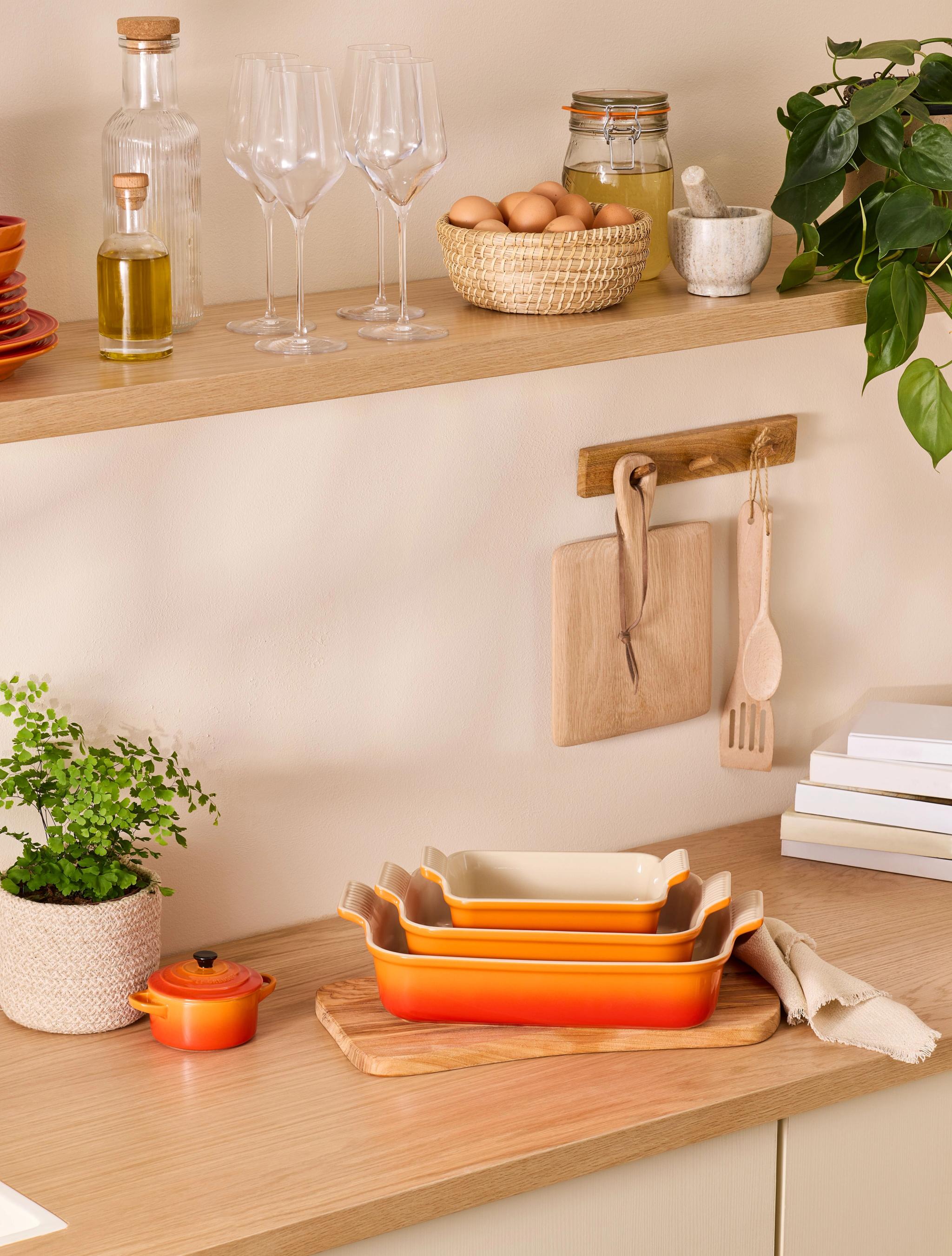 Oransje ildfast form fra Le Creuset som står på en kjøkkenbenk i tre