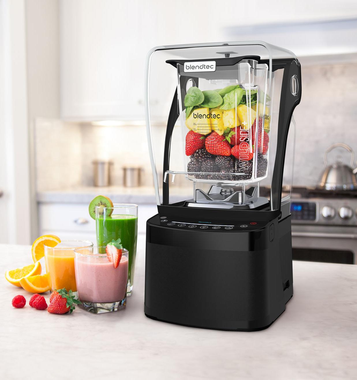 Tehokas Blendtec-tehosekoitin keittiön tasolla täynnä tuoreita hedelmiä ja marjoja, vieressä värikkäitä smoothieita laseissa.