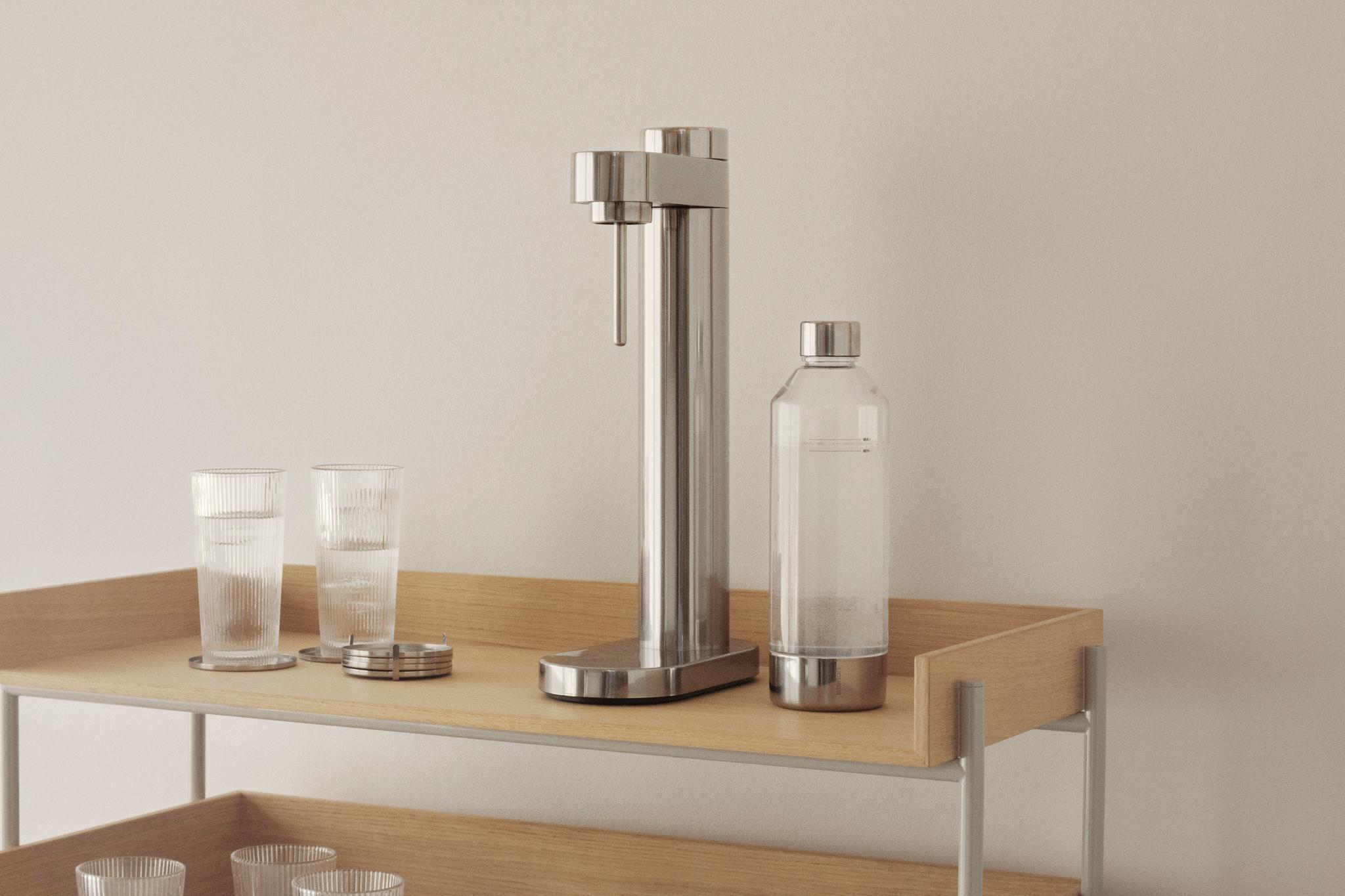 Minimalistisk kökshylla i ljust trä med sodastreamer, glas och karaff i ett skandinaviskt hem.