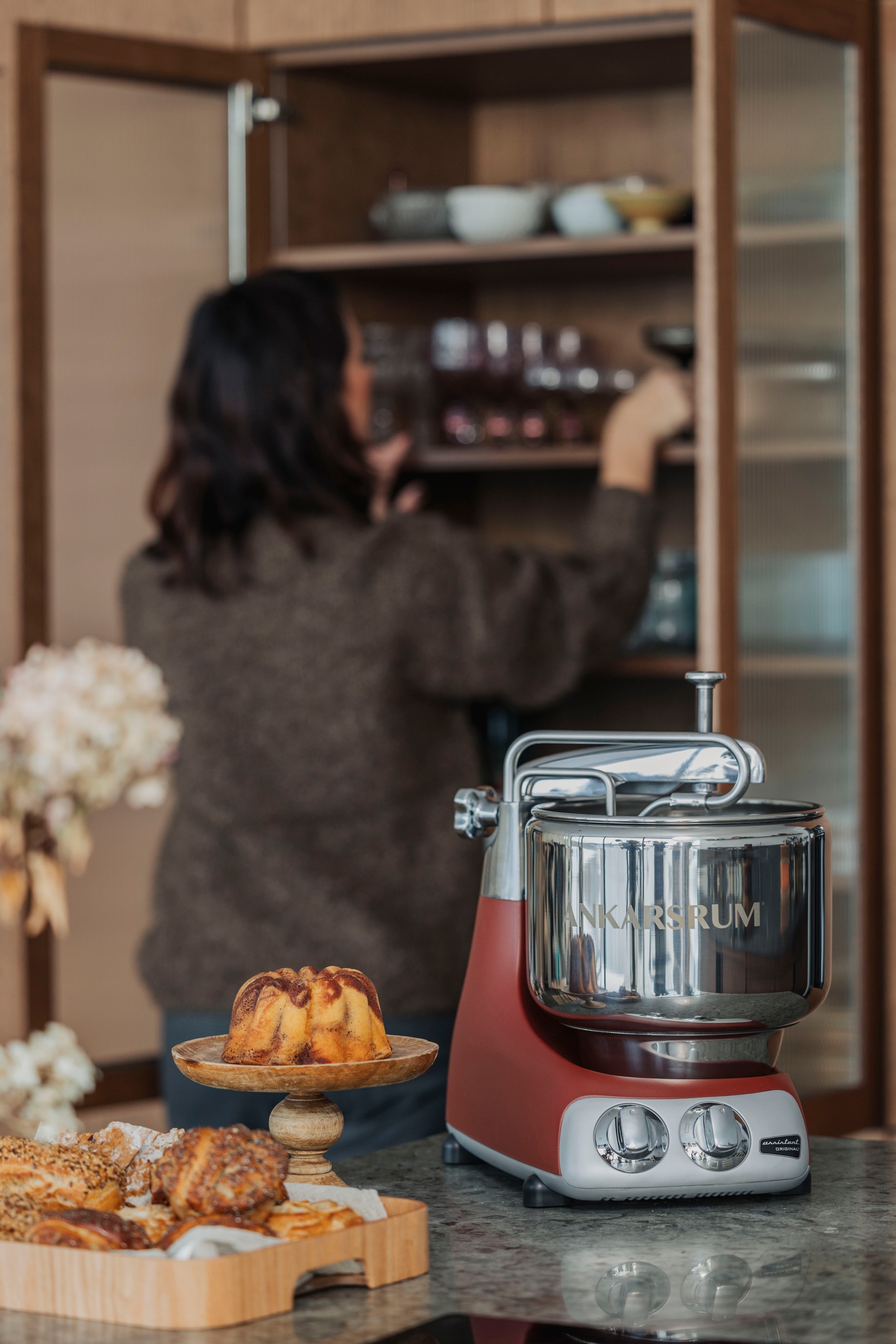 Ankarsrum Assisten köksmaskin uppställt på en grå bänkskiva med bullar omkring