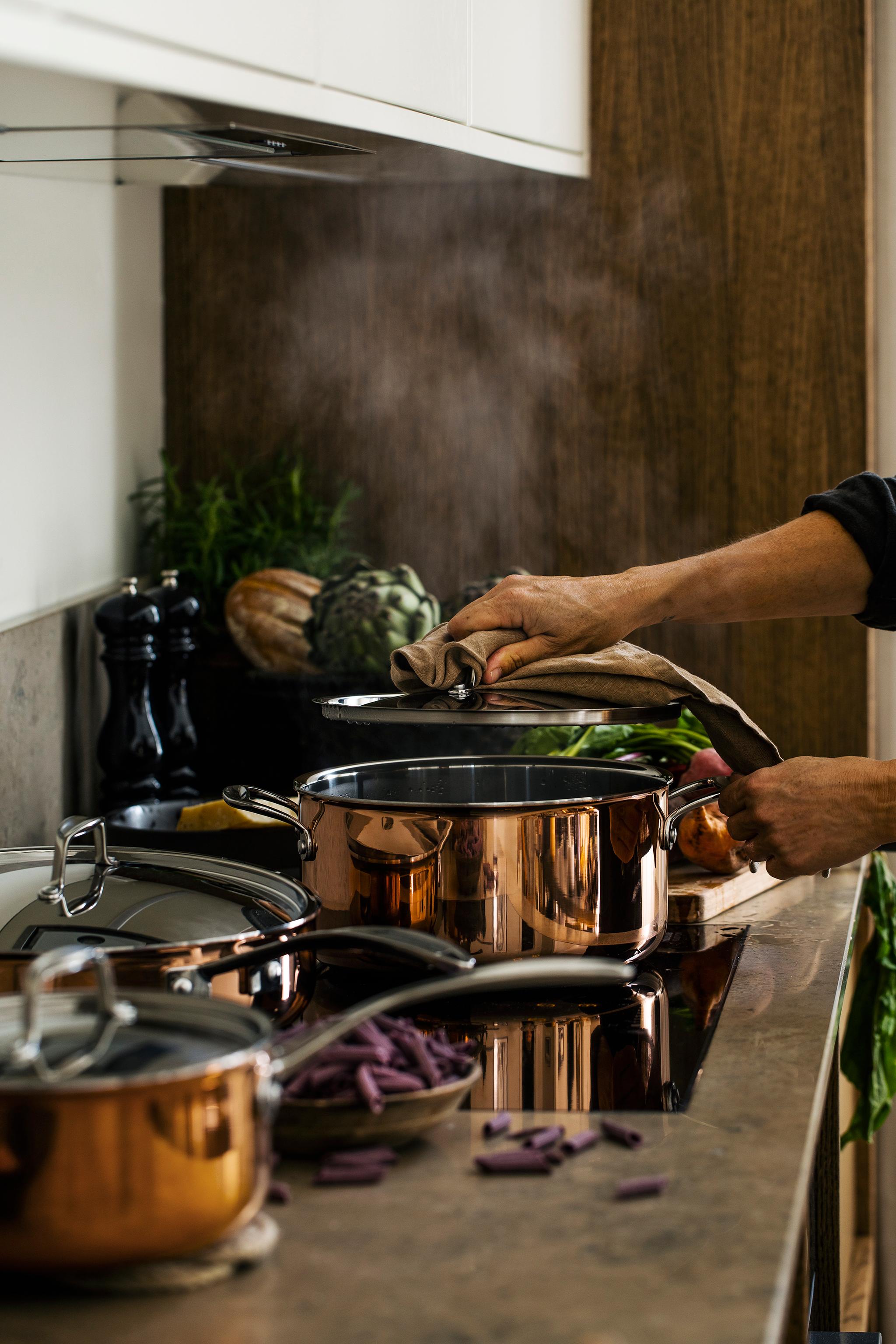 a person is cooking in copper pots in a kitchen