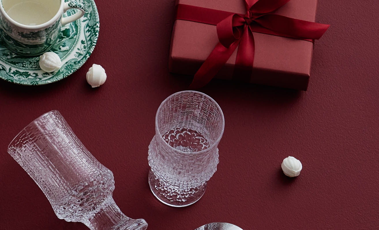 Ölglas från Iittala Kastehelmi och ett rött inslaget paket mot en röd bakgrund