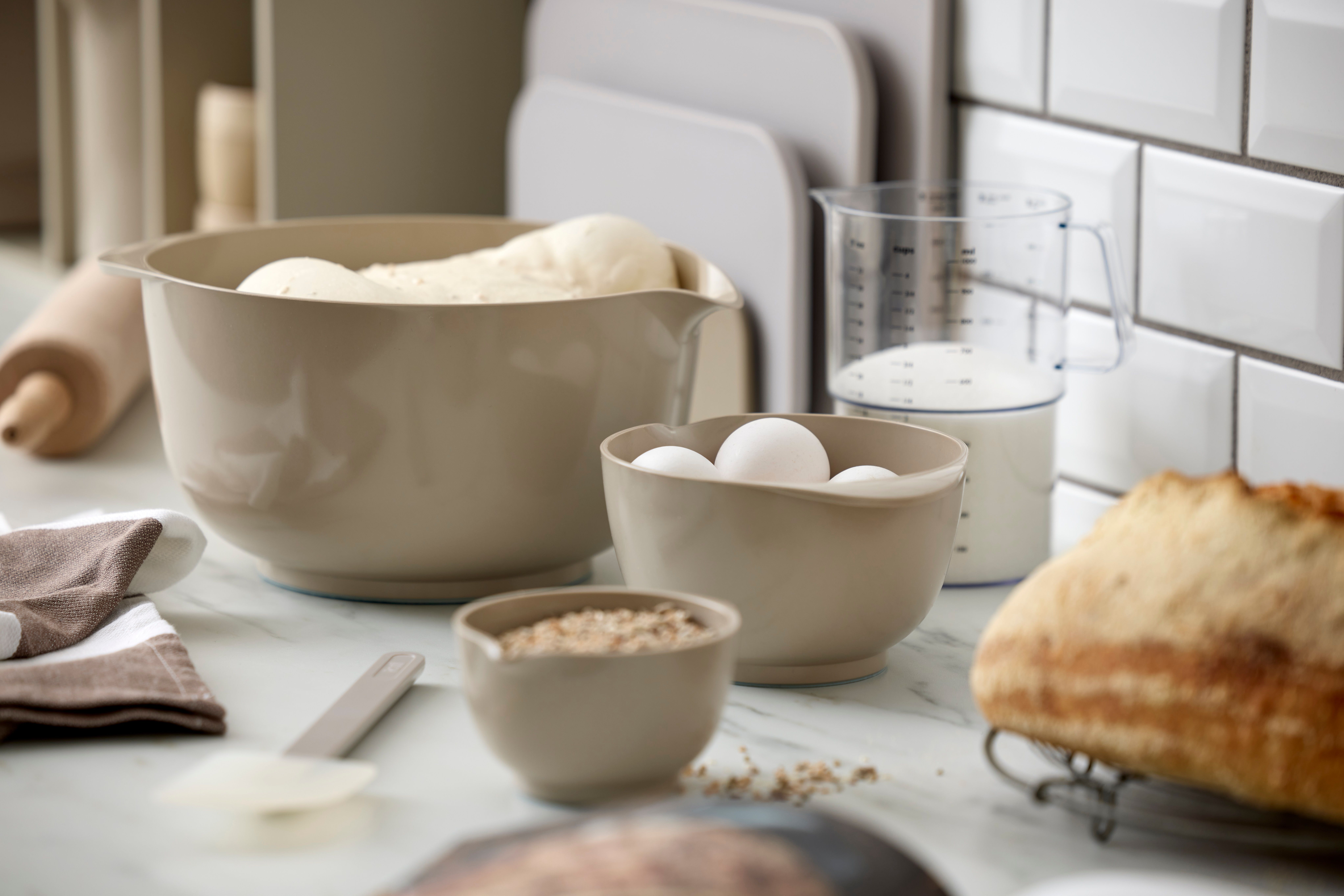 Bakning i köket med deg, ägg, havregryn, mjölk och nybakat bröd.