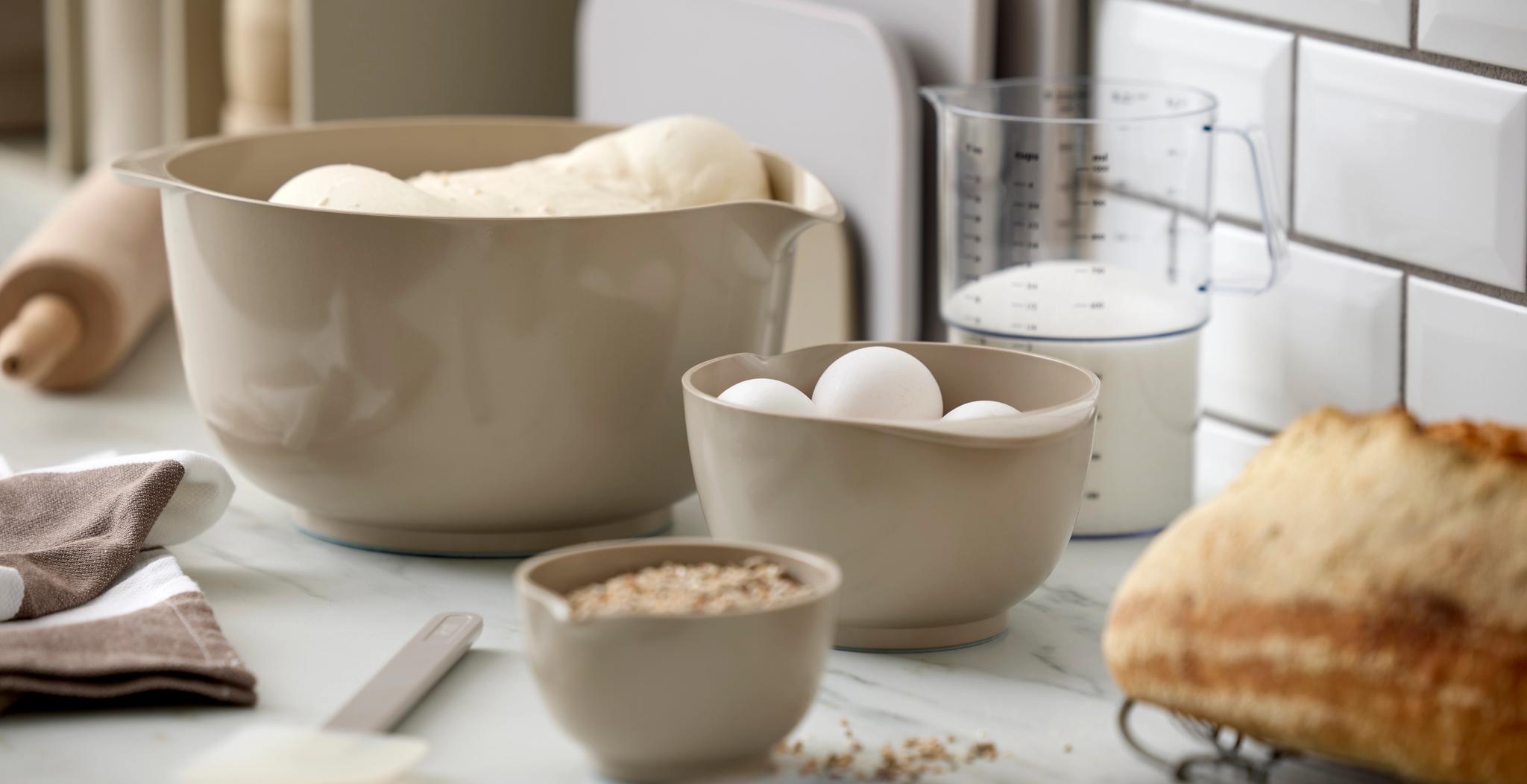 Bakning i köket med deg, ägg, havregryn, mjölk och nybakat bröd.