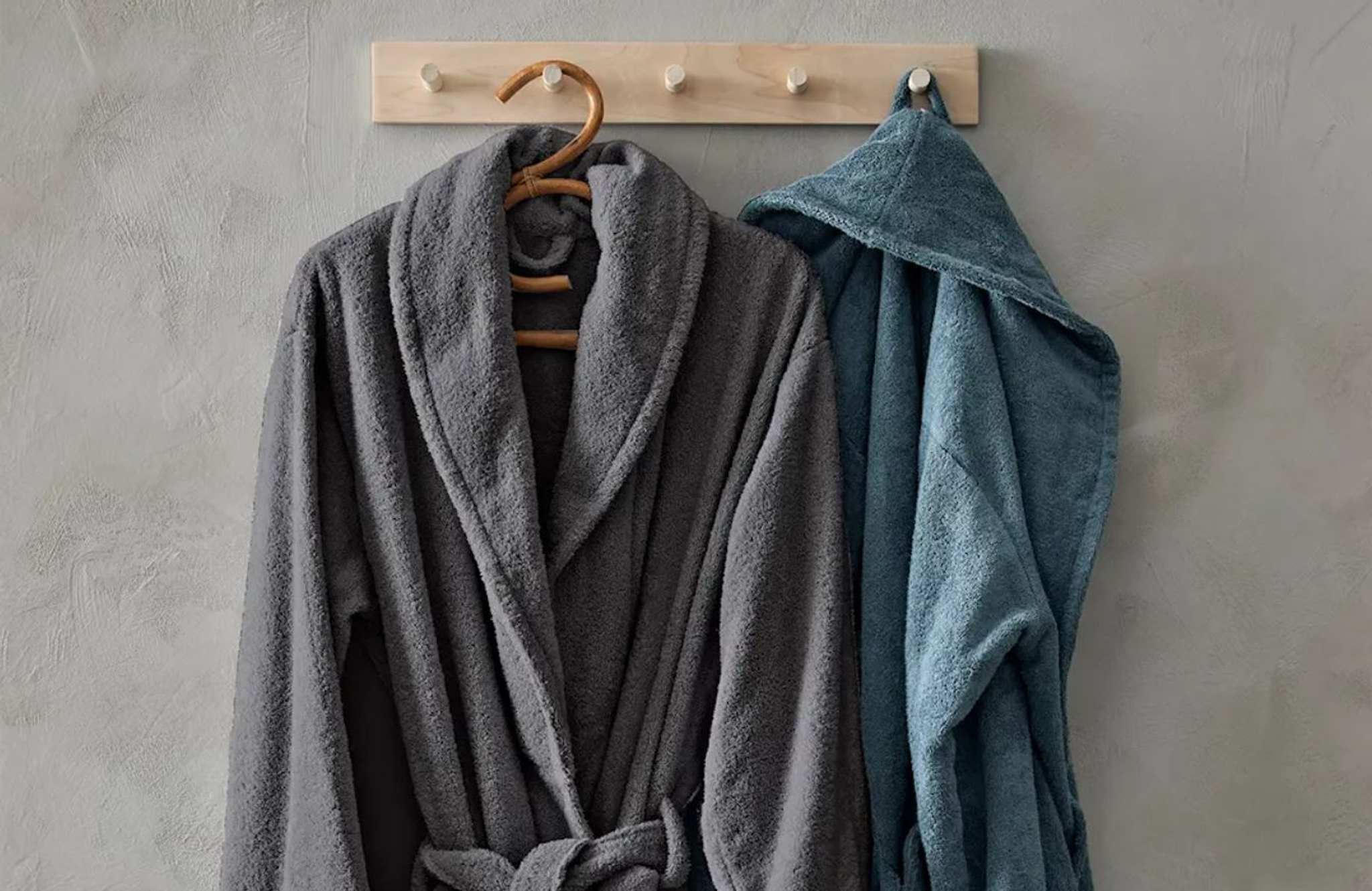 Två morgonrockar som hänger på en väggkrok i trä