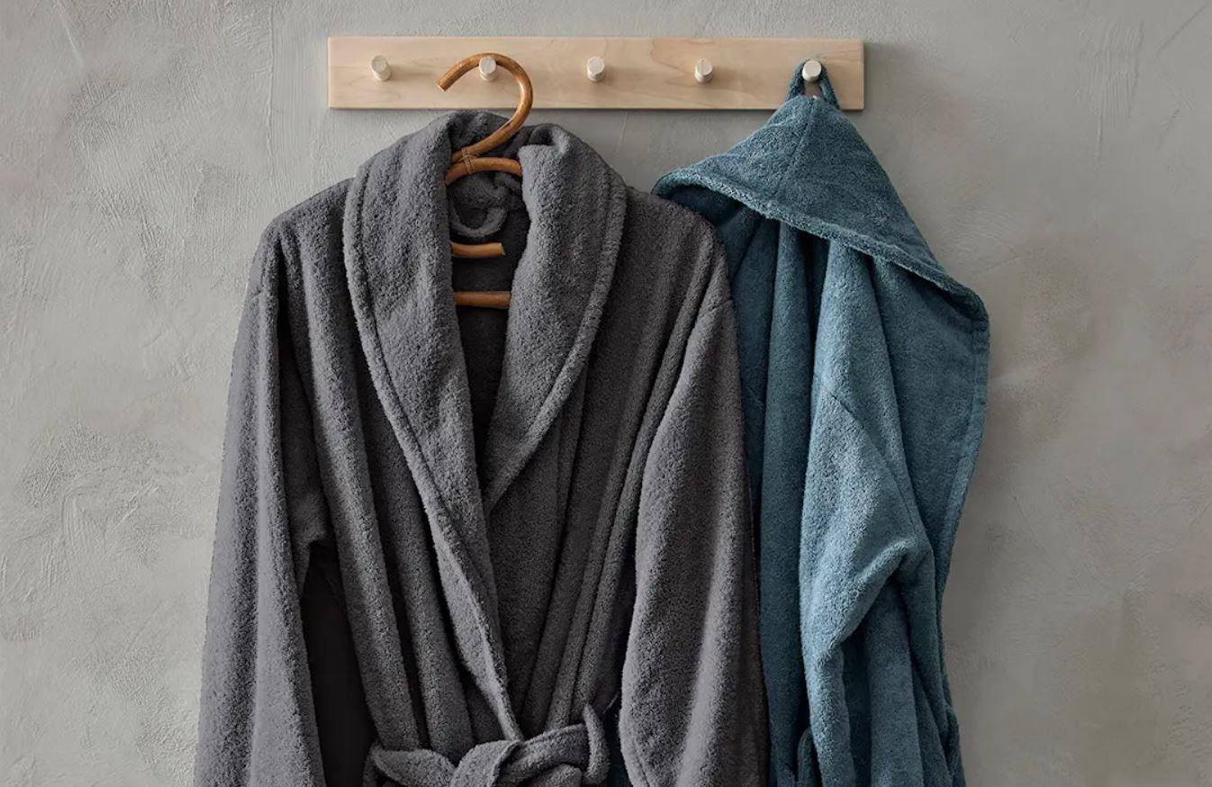 Två morgonrockar som hänger på en väggkrok i trä