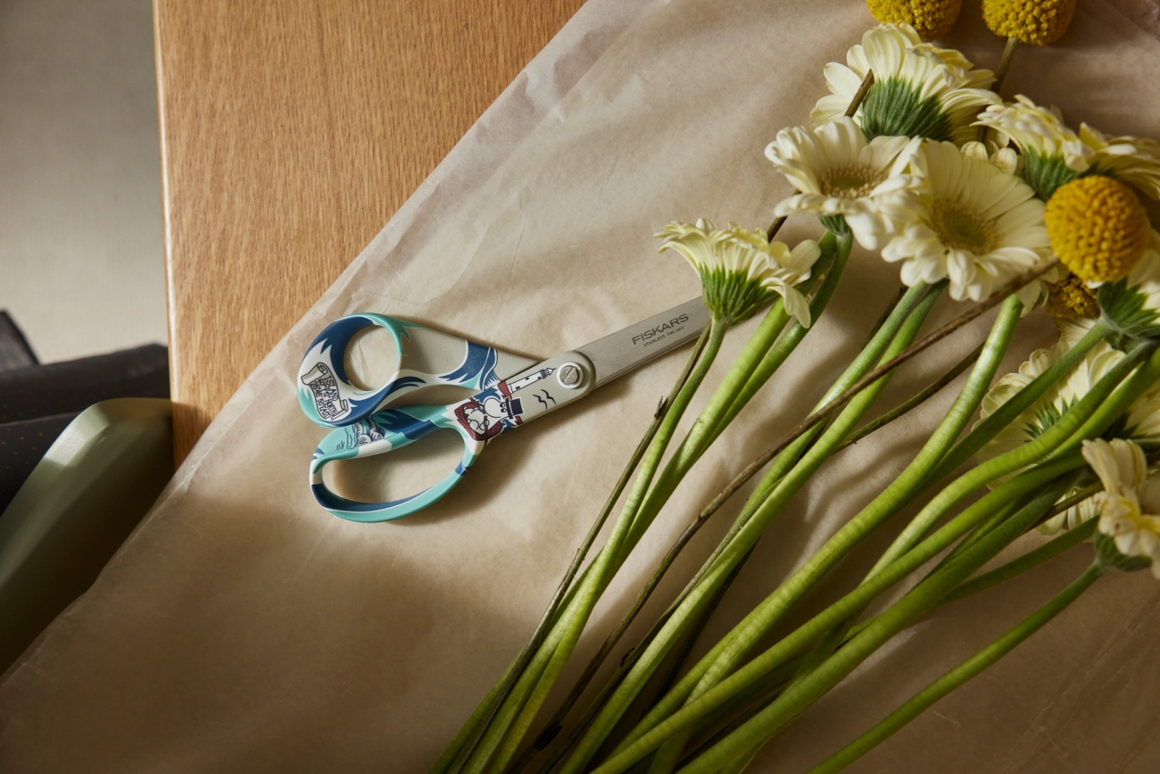 Fiskars muumisakset ja kukkakimppu pöydällä