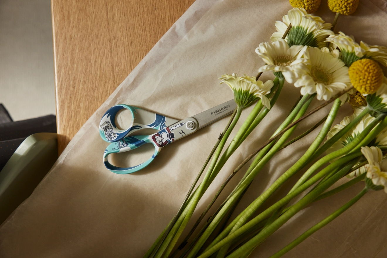 Fiskars muumisakset ja kukkakimppu pöydällä